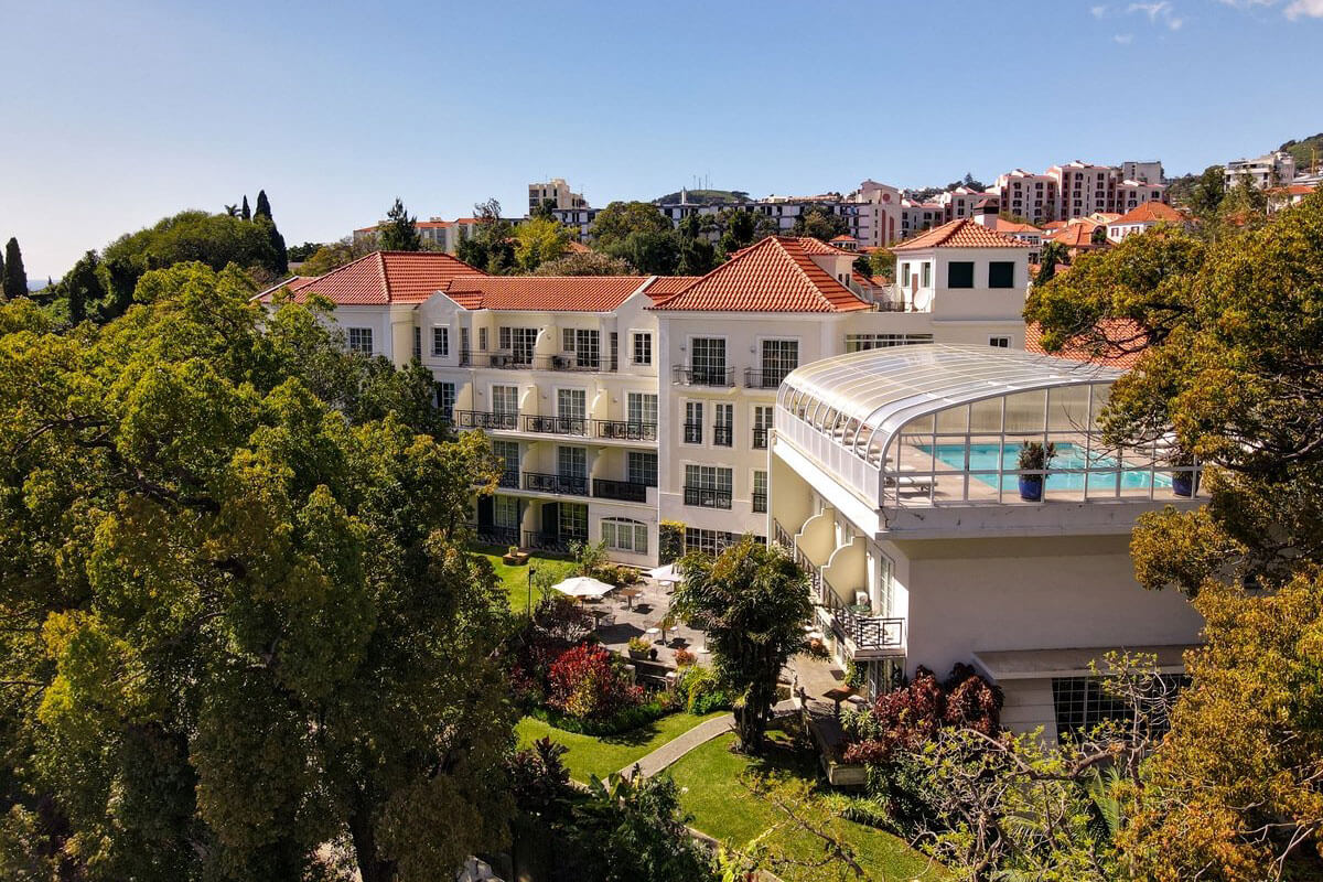 Vista aérea do Hotel Quintinha São João com vista para o jardim e piscina no topo de um dos edifícios.